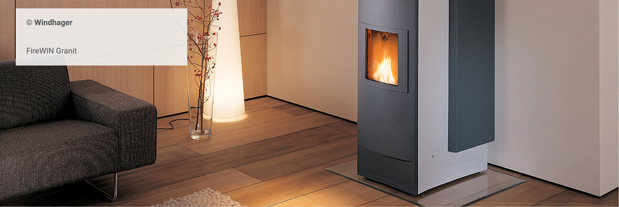 Moderner Pelletofen (Modell FireWIN Granit von Windhager) in einem stilvoll eingerichteten Wohnzimmer mit Holzboden und gemütlicher Atmosphäre