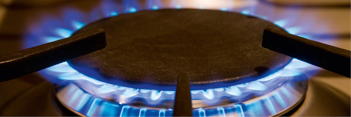 Ein Gasherd mit blauer Flamme, die einen schwarzen Topfträger umgibt – Symbol für Gas als Energiequelle im Haushalt