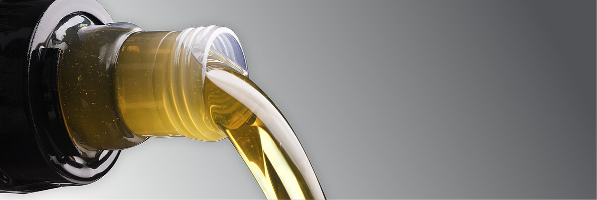 Ausgießende Flüssigkeit aus einer dunklen Flasche – symbolisiert Heizöl als fossile Energiequelle für Haushalte
