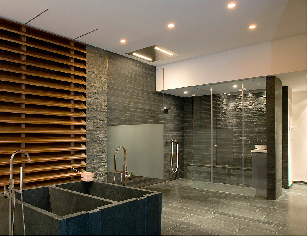 Luxuriöse Wellness-Suite mit eingelassener Dampfdusche und modernen Steinverkleidungen
