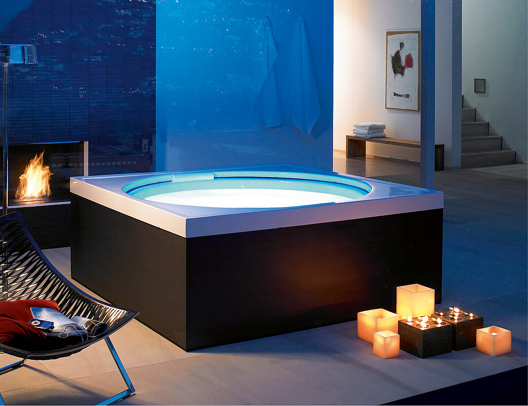 Outdoor-Whirlpool mit blauer LED-Beleuchtung und stimmungsvoller Kerzendekoration