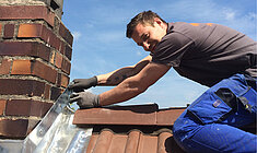 Handwerker installiert Dachziegel auf einem Hausdach - professionelle Handwerksleistungen