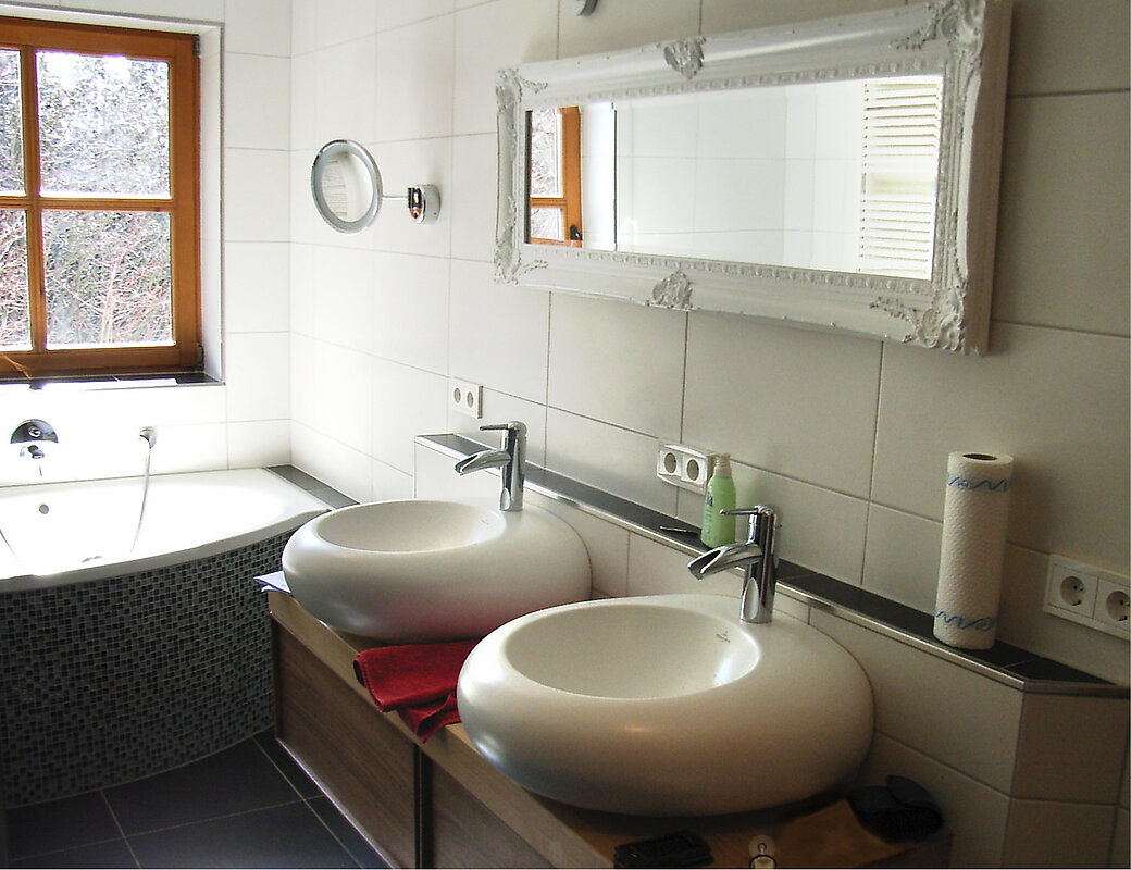 Modernes saniertes Badezimmer mit doppeltem Waschbecken, eleganten Armaturen und stilvoller Beleuchtung