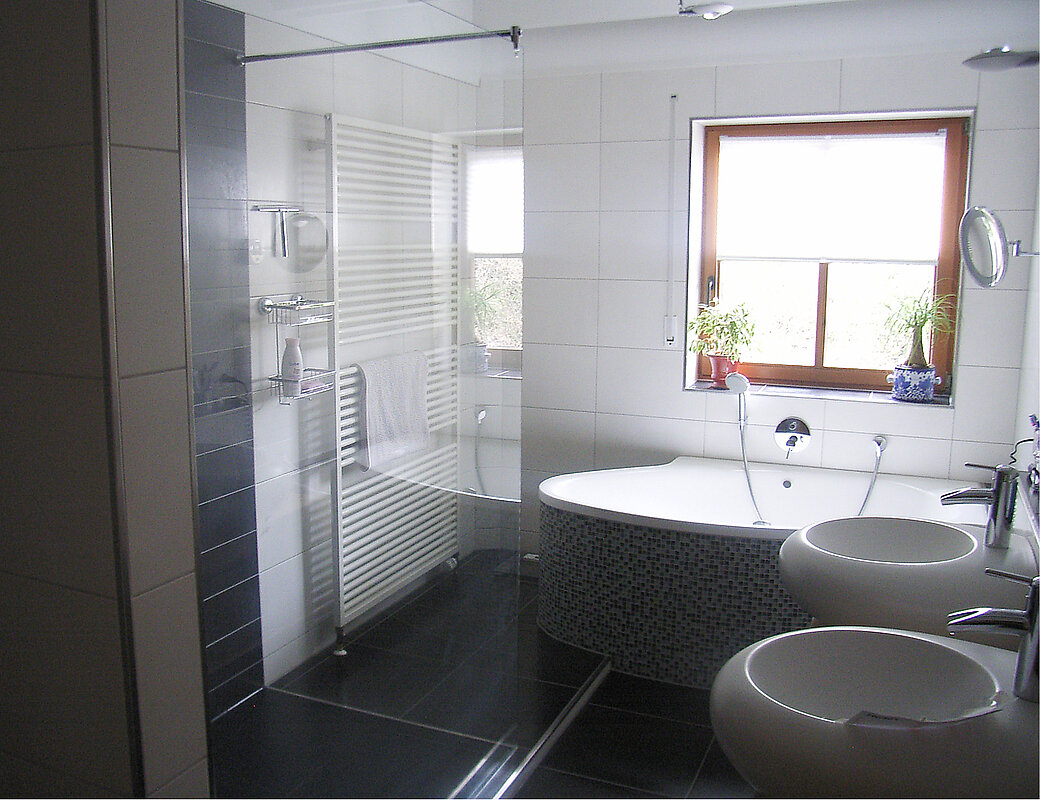 Luxuriöse neue Badewanne mit modernen dunklen Fliesen und Designer-Waschbecken nach der Sanierung