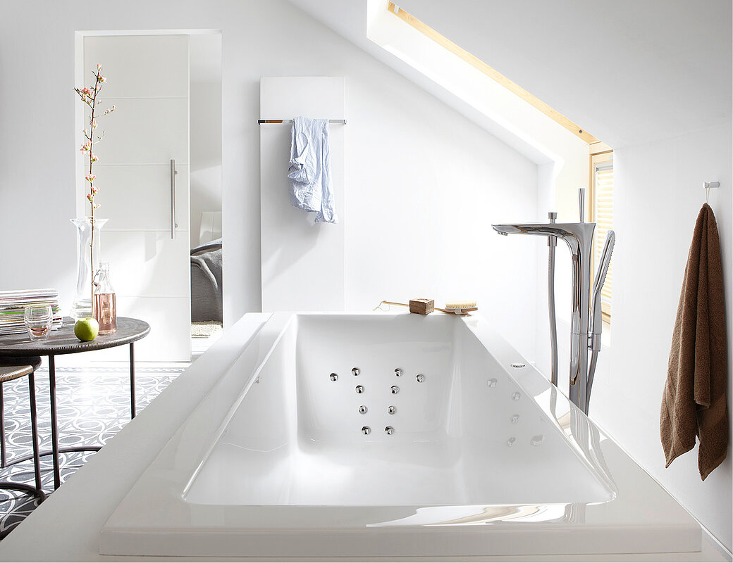 Elegante weiße Whirlpool-Badewanne mit Massagedüsen in modernem Badezimmer mit Dachschräge