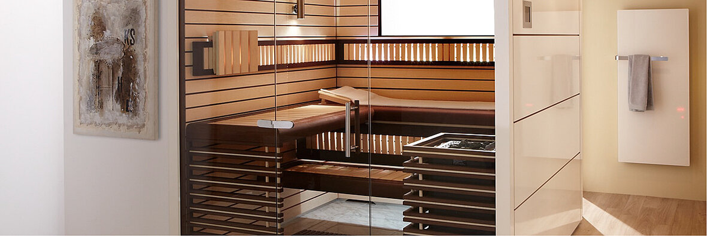 Moderne Holzsauna mit Glasfront, Liegebank und Ofen – daneben flacher Designheizkörper mit Handtuchhalter