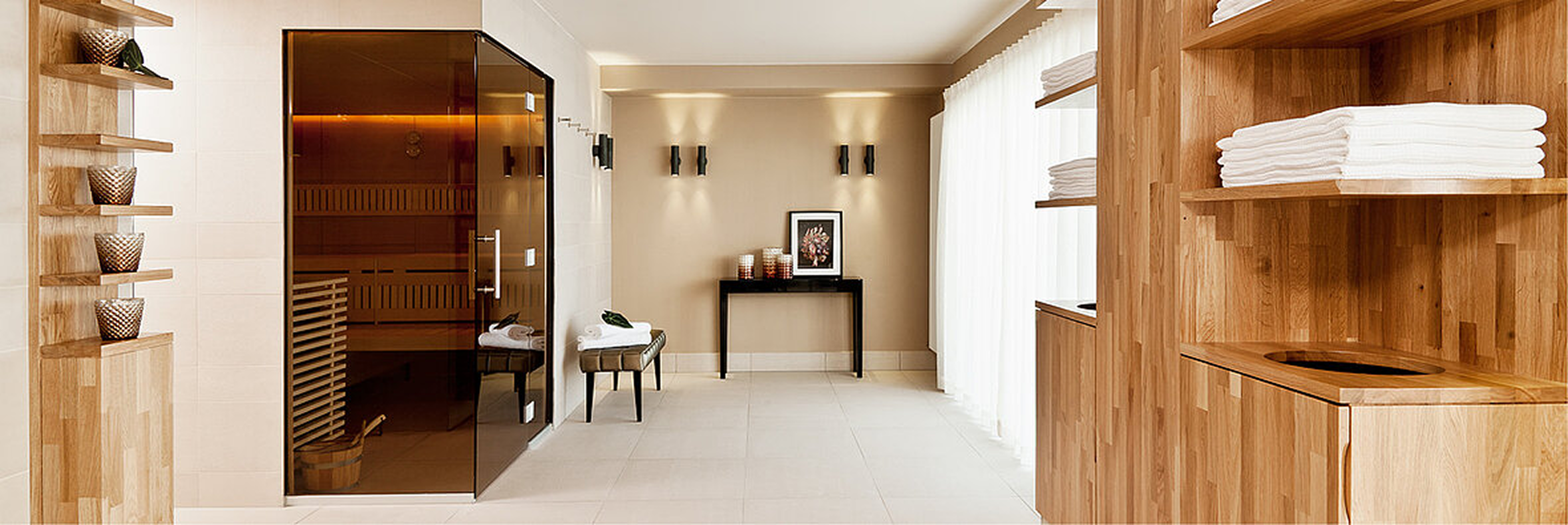 Moderner Spa-Ruheraum mit integrierter Holzsauna, weißen Handtüchern, minimalistischer Einrichtung und warmer Lichtstimmung