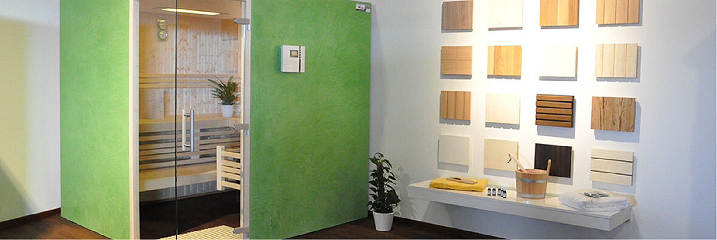 Moderne Sauna mit grüner Außenwand, Glasfront und gemütlichem Innenraum – daneben Auswahl verschiedener Holzarten zur individuellen Gestaltung